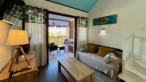 Een kamer met een houten tafel, een bank, een televisie en een balkon met uitzicht.