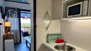 Een kleine keuken met een magnetron, spoelbak en opbergladen.