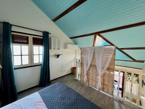 Ein Zimmer mit einem Bett, einem Vorhangfenster, einer Wandklimaanlage und einem Balkon mit einem Korbgitter.
