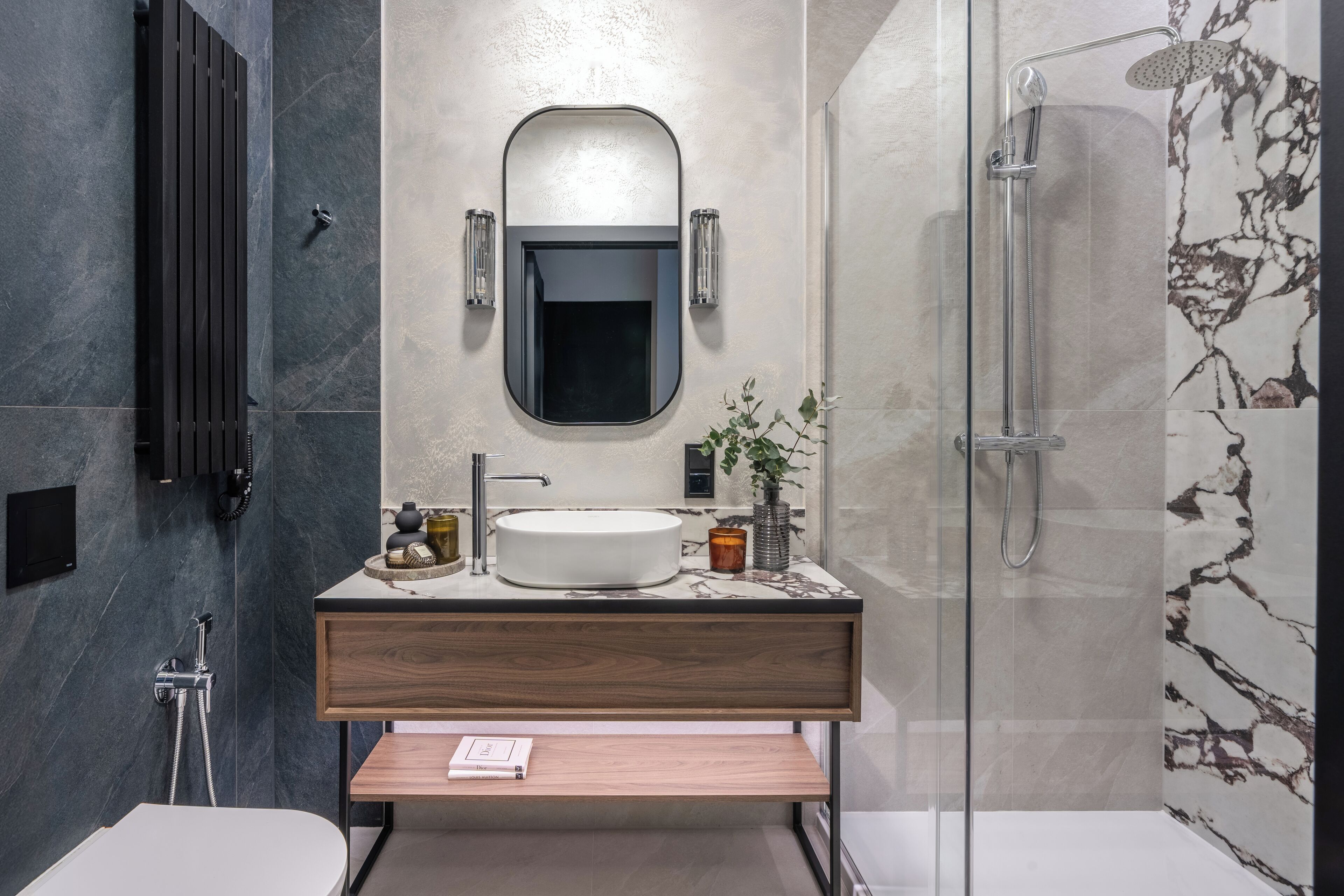 A modern bathroom with a freestanding bathtub, a round mirror, and a wooden vanity.
