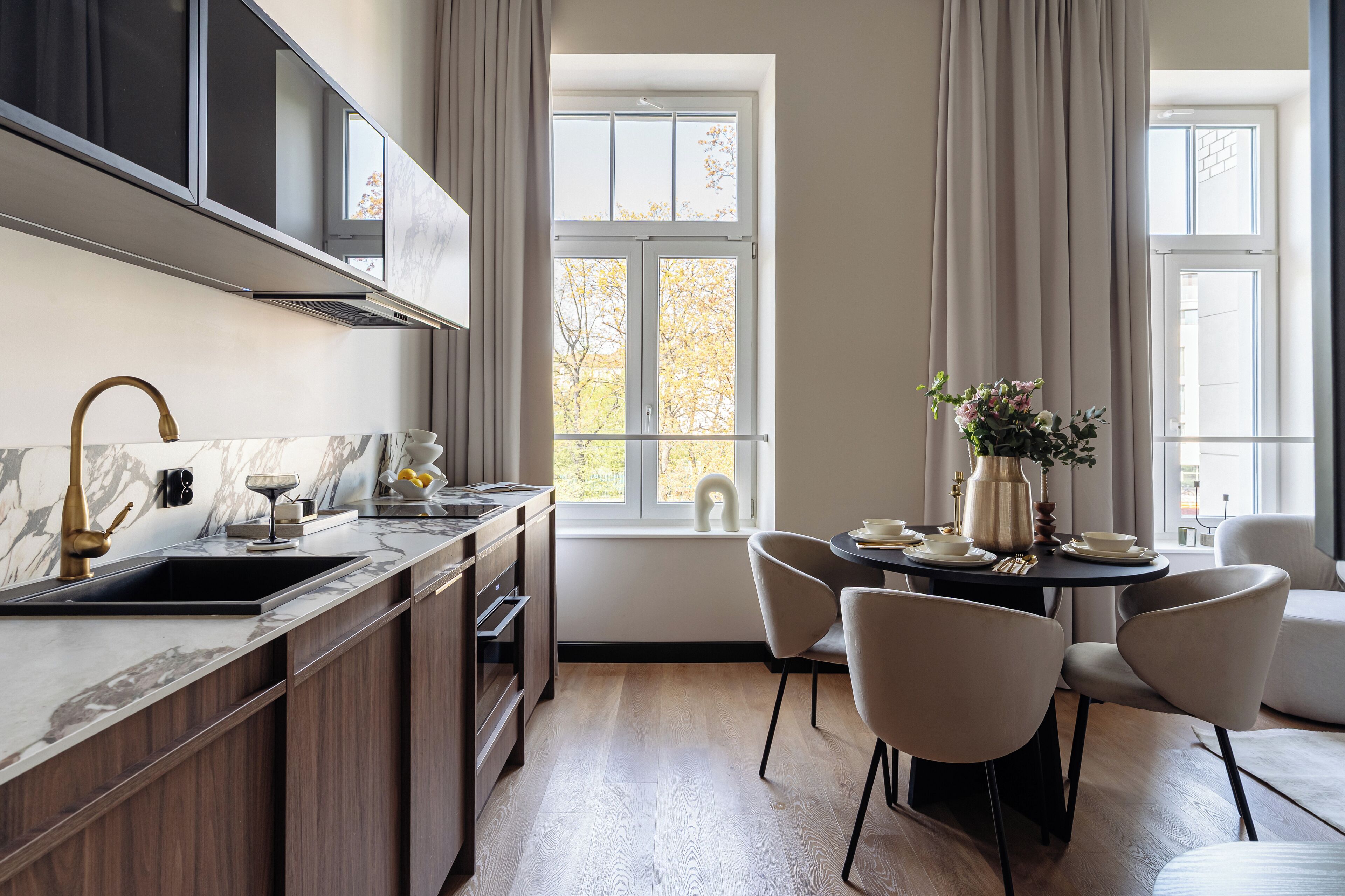 A modern kitchen with a marble countertop, wooden cabinets, and a dining area with a table and chairs.
