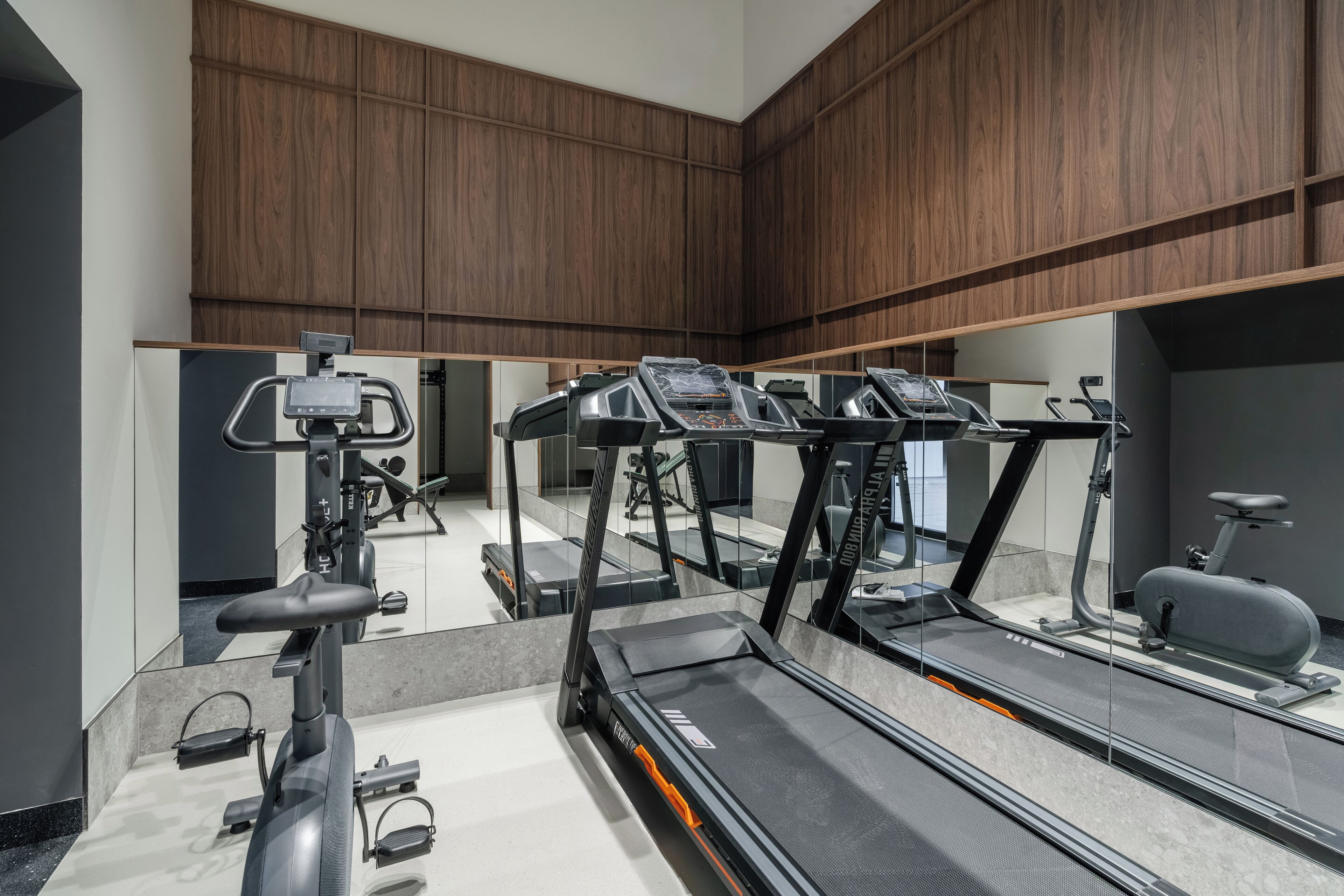 A modern gym with treadmills, stationary bikes, and a rowing machine.