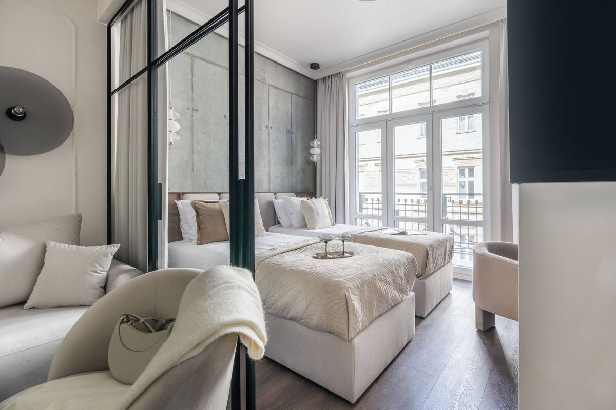 Une chambre d’hôtel moderne avec une grande fenêtre, un canapé, un lit et un fauteuil.