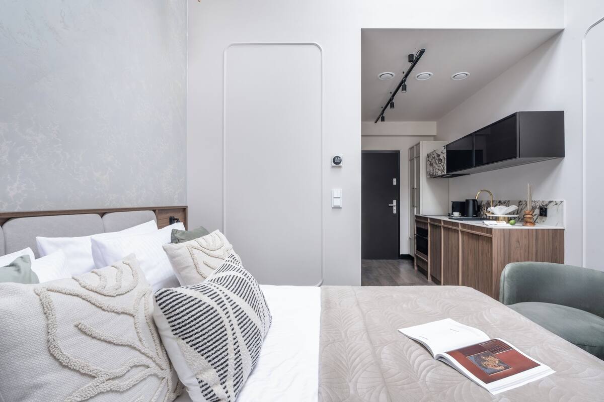 Une chambre d’hôtel moderne équipée d’un lit, d’un petit bureau et d’une kitchenette.