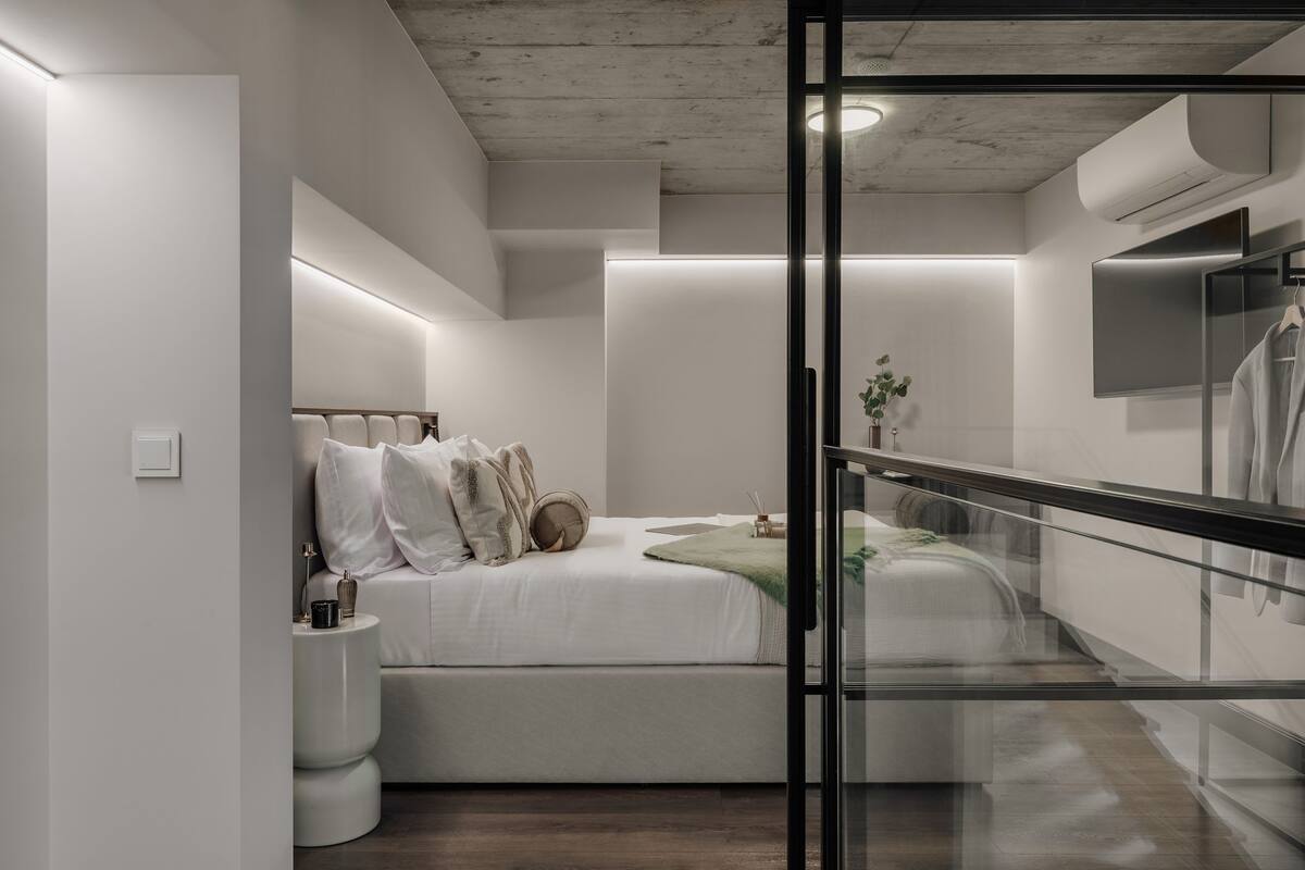 Une chambre à coucher moderne avec un lit, une table de chevet et une cloison en verre.