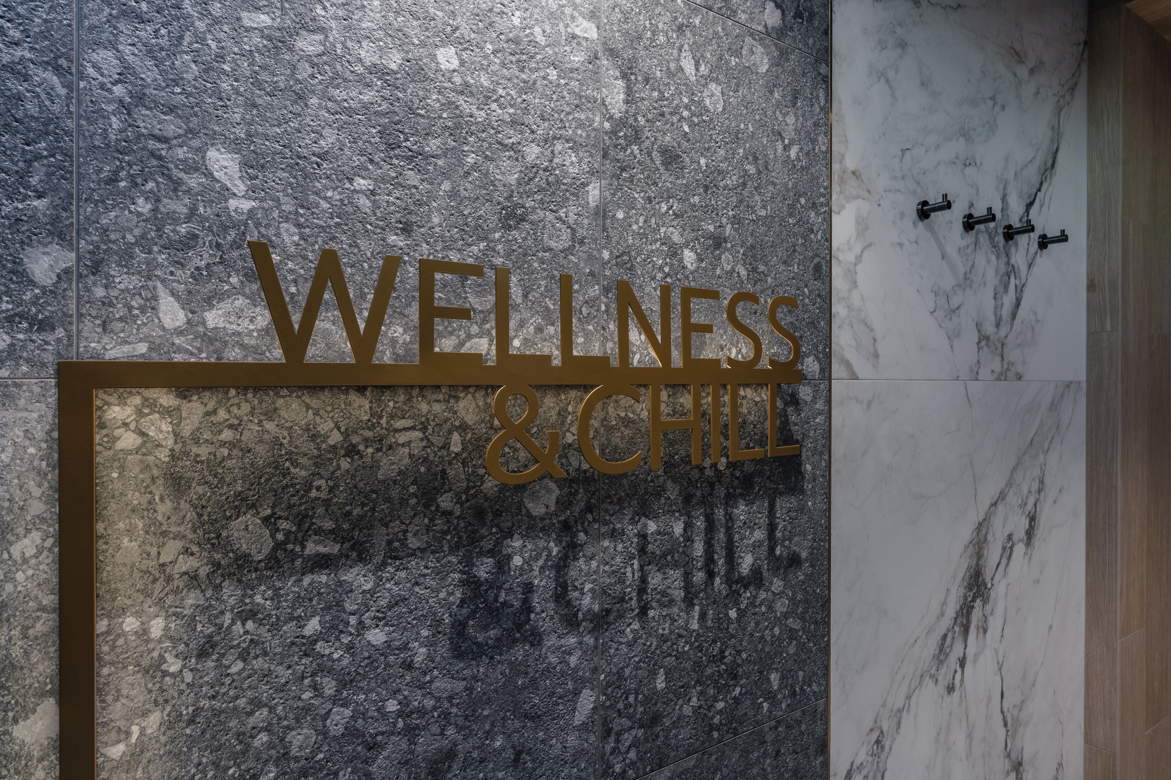 Ein Schild mit der Aufschrift "WELLNESS & CHILL" an einer strukturierten Wand.