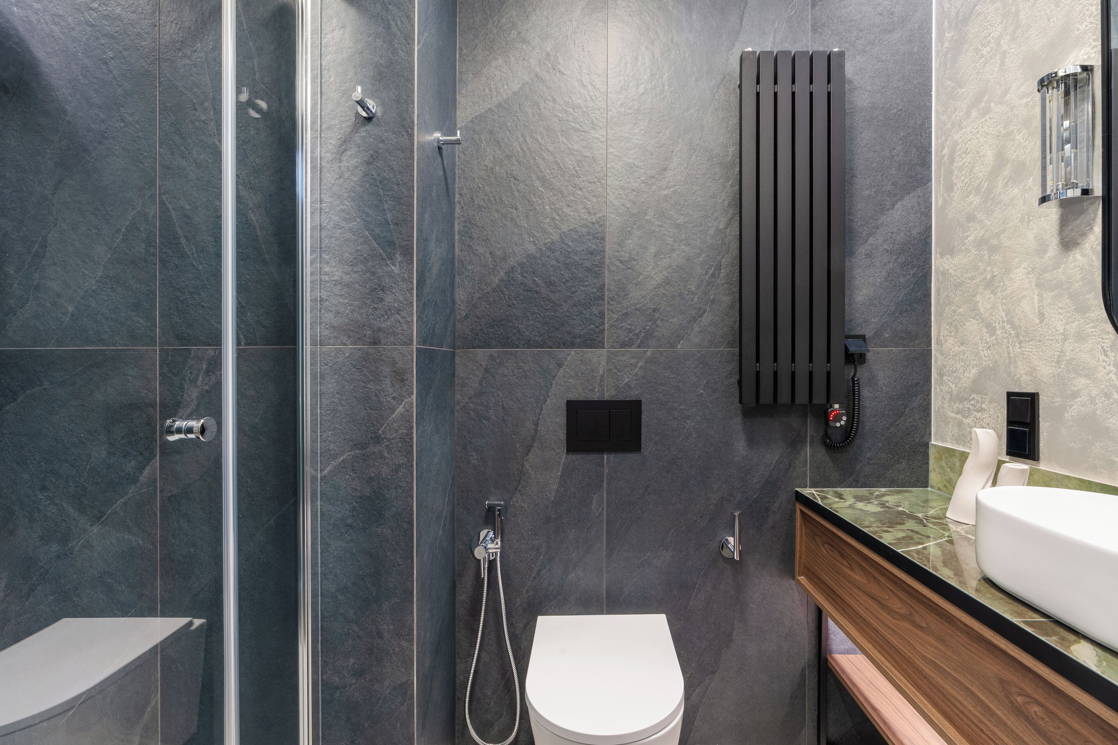 Een moderne badkamer met een douchecabine van glas, een wit toilet en een wastafelmeubel met een wastafel.