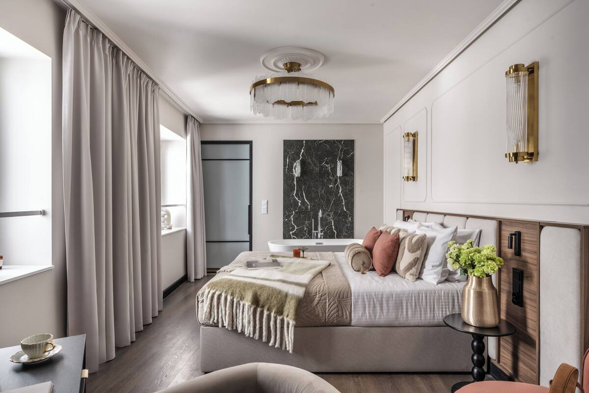 Une chambre moderne avec un grand lit, une table de chevet, une commode, une fenêtre avec des rideaux, un lustre et une œuvre d’art en marbre accrochée au mur.