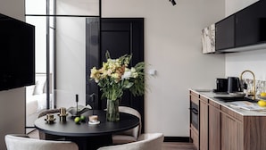 Une cuisine moderne avec un coin repas, comprenant une table ronde entourée de chaises, un vase de fleurs et une porte à cadre noir.
