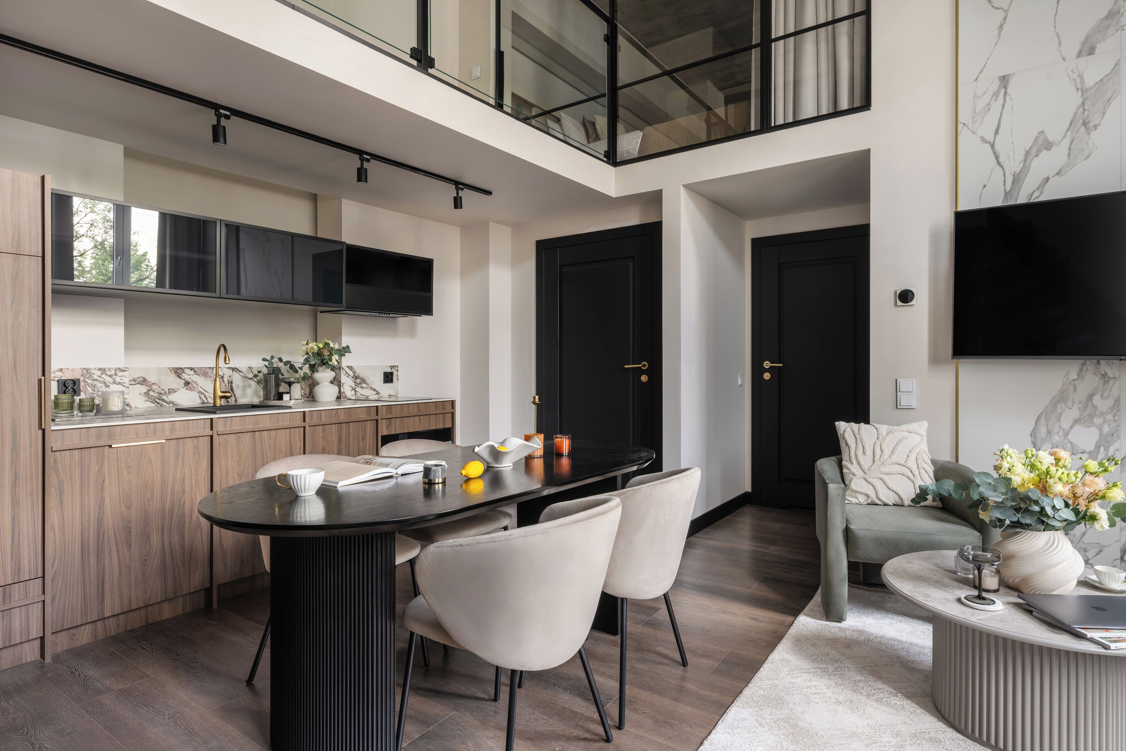 A modern kitchen with a dining area, a sofa, and a TV.
