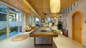 A pool table in a well-lit room with a ceiling fan, large windows, and a view of the outdoors. - Panorama Paddy Retreat - Luxury Villa & Pool (Thành phố Hội An)