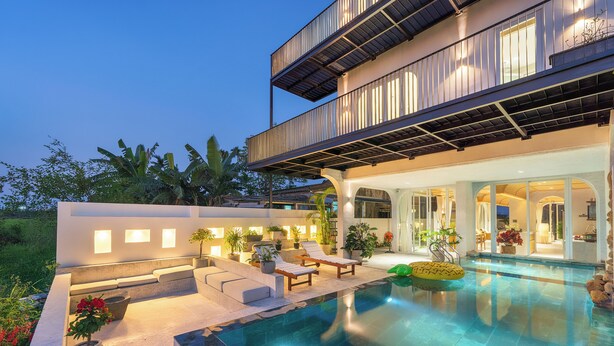 A modern outdoor pool area with a two-story building, seating, and potted plants. - Panorama Paddy Retreat - Luxury Villa & Pool (Thành phố Hội An)