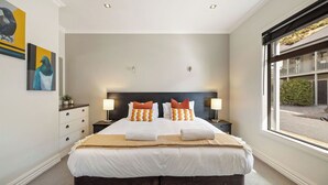 A hotel bedroom with a large bed, two bedside tables with lamps, a headboard, and artwork on the wall. - Cardrona Retreat, Resort spa & swimming pool (Cardrona)