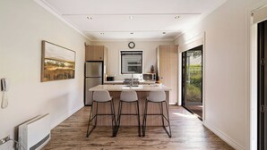 A modern kitchen with a central island, bar stools, a microwave, and a refrigerator. - Cardrona Retreat, Resort spa & swimming pool (Cardrona)