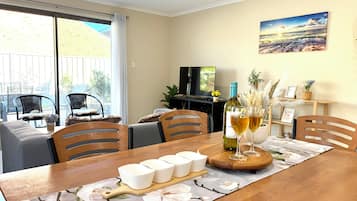 A dining area with a wooden table, chairs, a TV, and a painting on the wall.