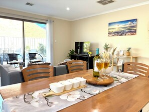 Un comedor con una mesa de madera, sillas, un televisor y un cuadro en la pared.