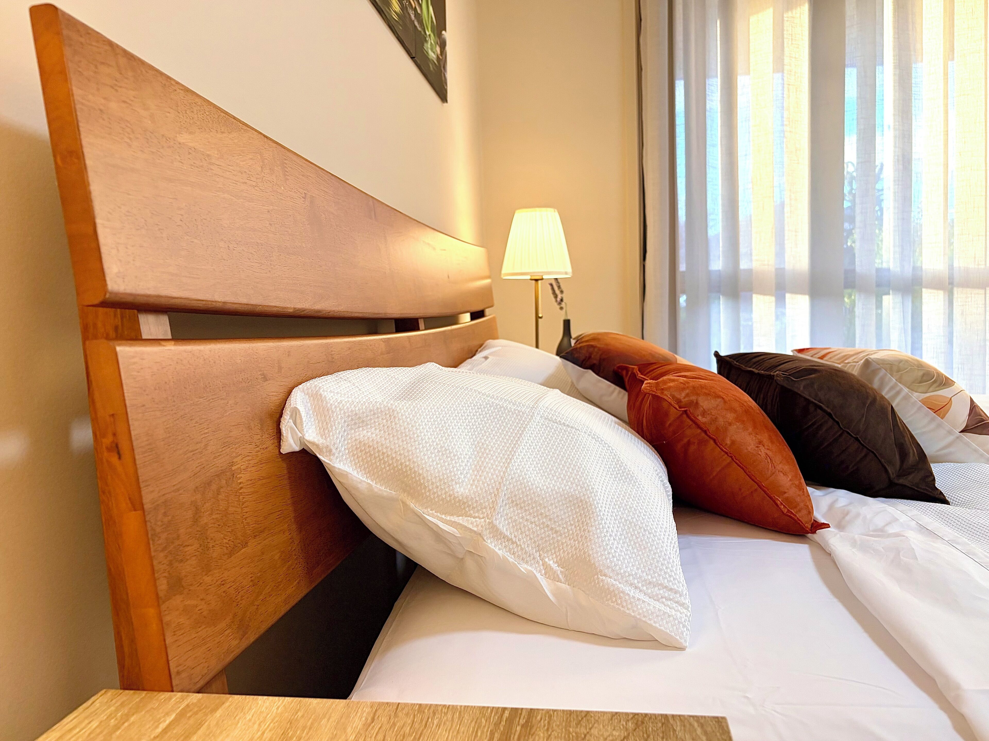 Ein Hotelzimmer mit einem hölzernen Kopfende, weißer Bettwäsche und einer Lampe.