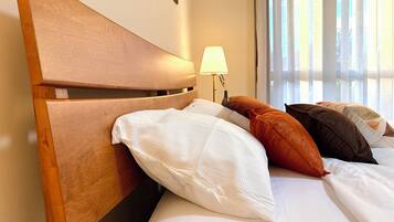 Ein Hotelzimmer mit einem hölzernen Kopfende, weißer Bettwäsche und einer Lampe.