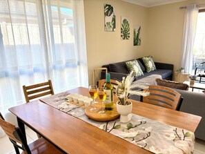 A dining area with a wooden table, chairs, and a bottle of wine. - Beach&Winery Getaway| Spacious 5BR Premium King, 2Q, NBN, Neflix, sleeps12 (Christie Downs)