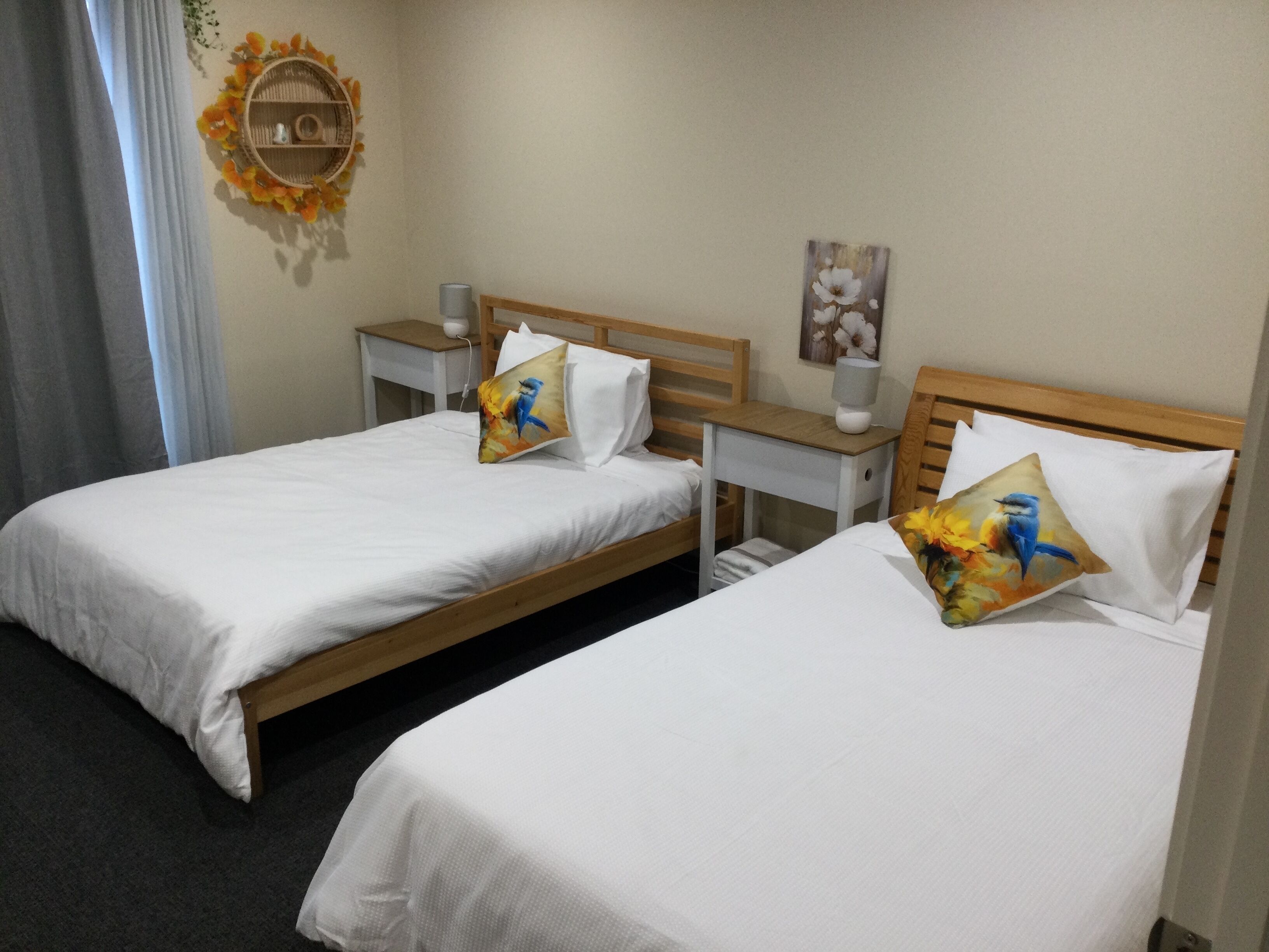 A hotel room with two single beds, each with a pillow and a bedside table with a lamp.