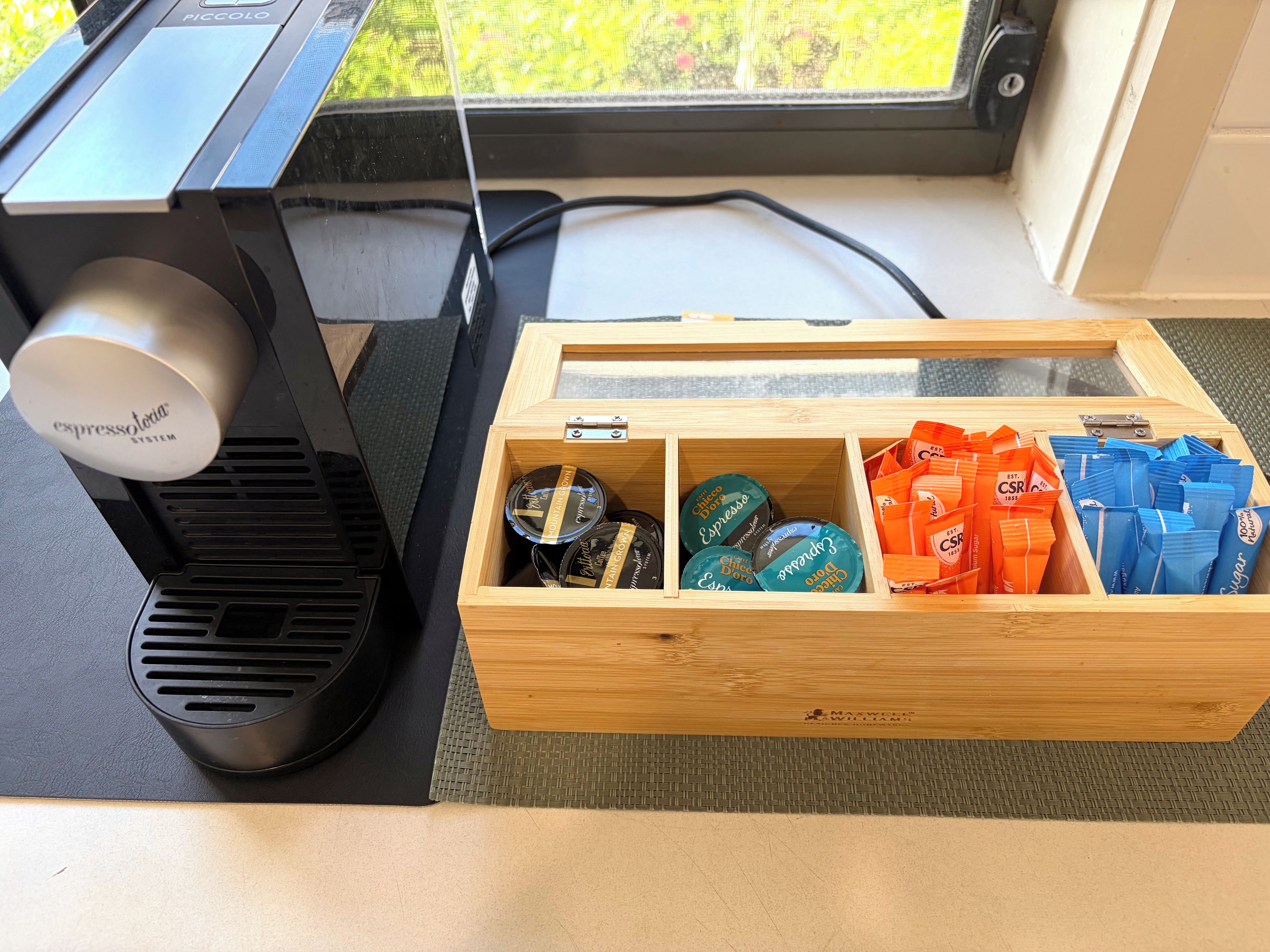 A coffee machine and a wooden box with coffee pods and capsules.