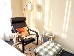 A room with a black leather chair, a wooden floor, a small table with a cup and a magazine, and a lamp. - Beach&Winery Retreat| Premium King, 2Queen, 5BR 2Bath, Neflix, sleeps12, Max13 (Christie Downs)