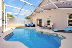 Una piscina interior con techo de vidrio, sillones de descanso y zona de estar.