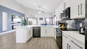 A modern kitchen with white cabinetry, a dishwasher, a stove, and a microwave. - Fully Renovated Disney Villa with Private Pool, King size Beds in Davenport (Davenport)