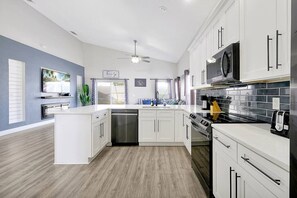 Una cocina moderna con muebles blancos, lavavajillas, estufa y microondas.