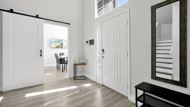A hallway with a sliding door, a dining area with chairs and a table, and a large mirror on the wall. - Fully Renovated Disney Villa with Private Pool, King size Beds in Davenport (Davenport)