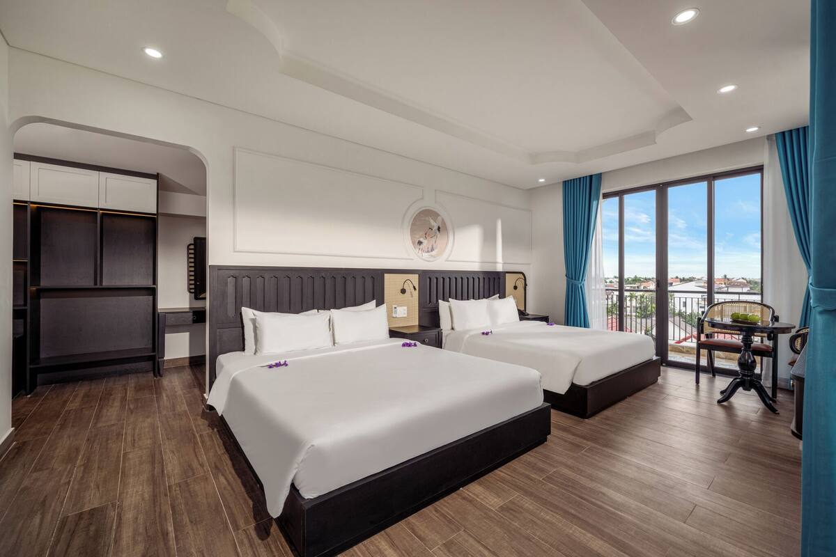 Habitación de hotel con dos camas, un balcón y vistas, además de un armario.