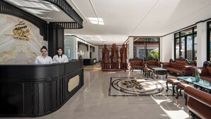 Un hall d’hôtel comprenant un comptoir d’accueil, un espace salon et un motif décoratif sur le sol.