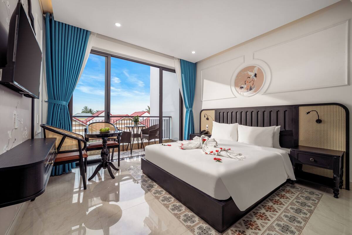 Habitación de hotel moderna con una cama grande, un escritorio y un balcón con vistas.