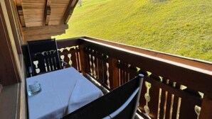 A balcony with a table and chairs, overlooking a grassy hillside. - Stallon apartment with balcony (Nostra)