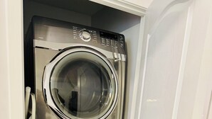 A compact, stainless steel, two-door washer and dryer unit with a control panel and a 10-year warranty sticker. - 2-bedroom apartment in wonderful SW Edmonton with WiFi, fitness equipment. (Edmonton)