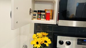 A kitchen with a microwave, stove, and a shelf with jars and a can. - 2-bedroom apartment in wonderful SW Edmonton with WiFi, fitness equipment. (Edmonton)