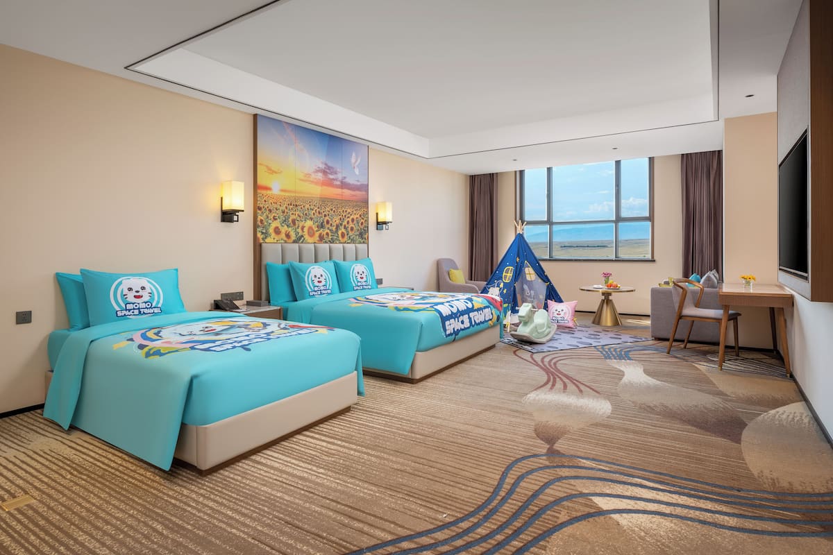 A hotel room with two beds, a desk, a chair, a small table, and a large window with a view.