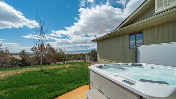 A hot tub with a view of a grassy yard and distant hills. - Sunset Ridge (Penrose)