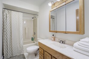 Bathroom features a toilet, bathtub, sink, and mirror.