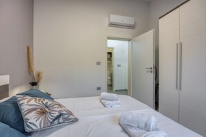 A hotel room with a bed, a wardrobe, and an air conditioning unit.