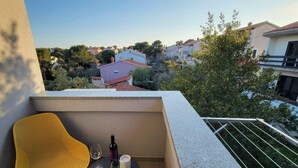 A balcony with a yellow chair, a small table, and a bottle of wine. - Royal Premantura (Medulin)