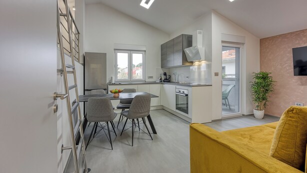 A modern kitchen with a dining area, a staircase, and a living area with a sofa. - Royal Premantura (Medulin)