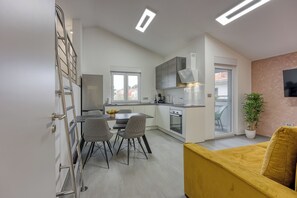 A modern kitchen with a dining area, a staircase, and a living area with a sofa. - Royal Premantura (Medulin)