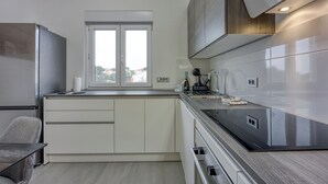 A modern kitchen with a large window, built-in appliances, and a minimalist design. - Royal Premantura (Medulin)