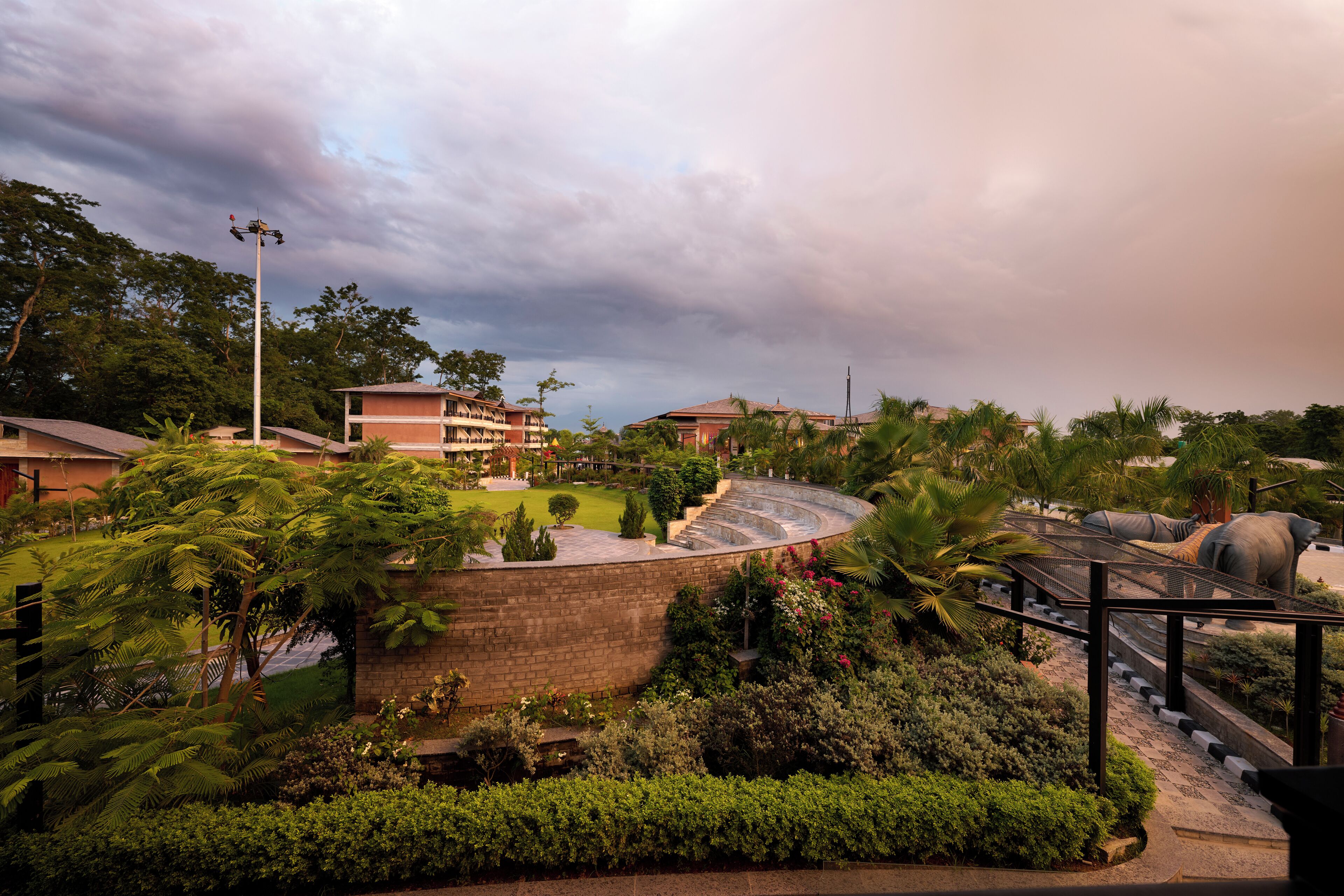 A landscaped area with a curved pathway, a brick wall, and a large elephant statue.