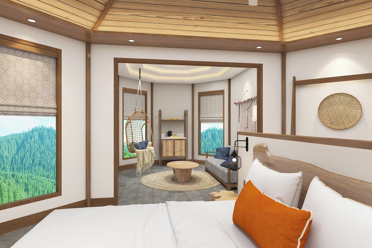 Ein Schlafzimmer mit einem großen Bett, einem Hängesessel, einem kleinen Tisch und Blick auf einen Wald durch große Fenster.