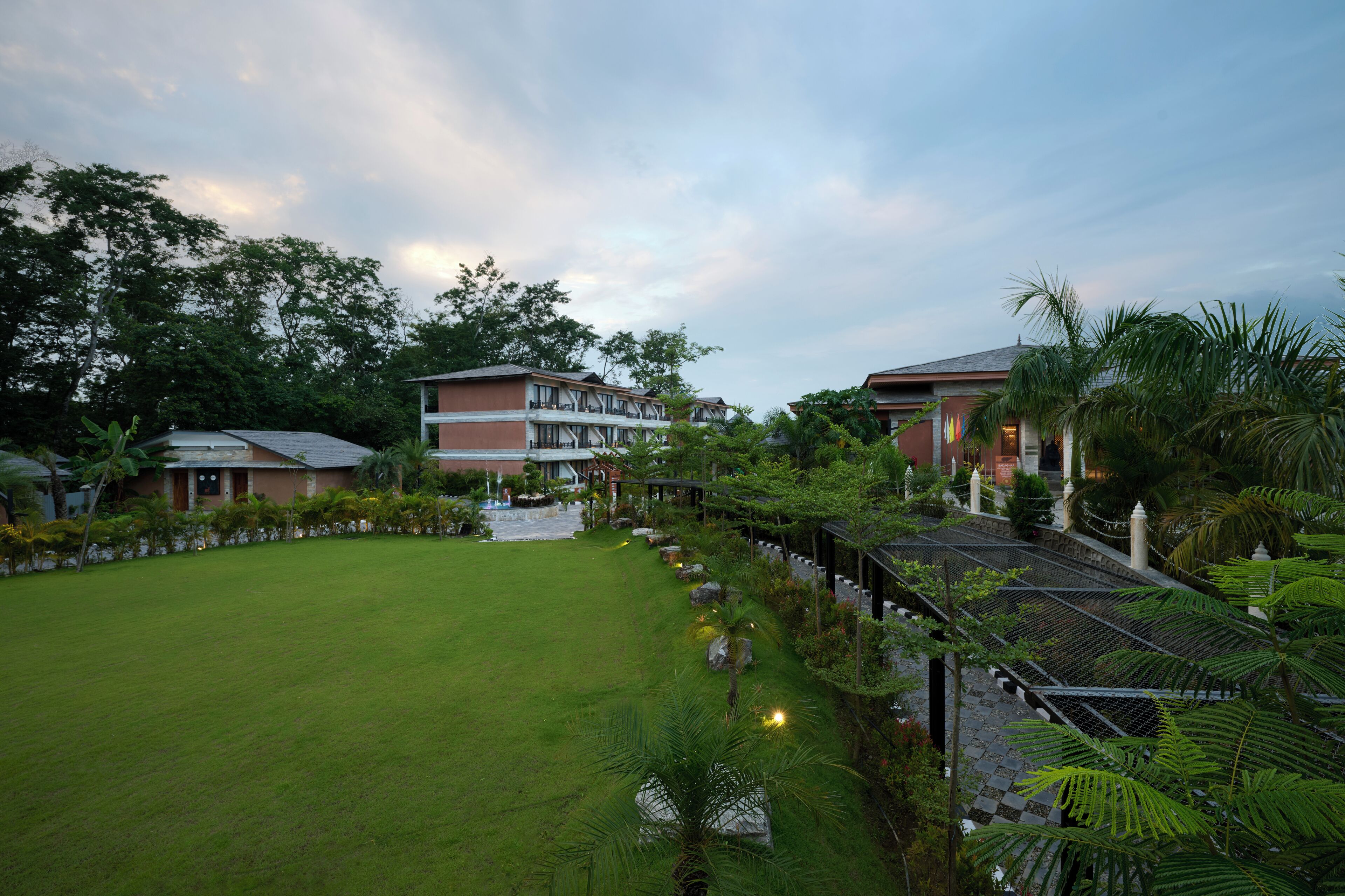 Un patio de hotel con césped, senderos y plantas tropicales.