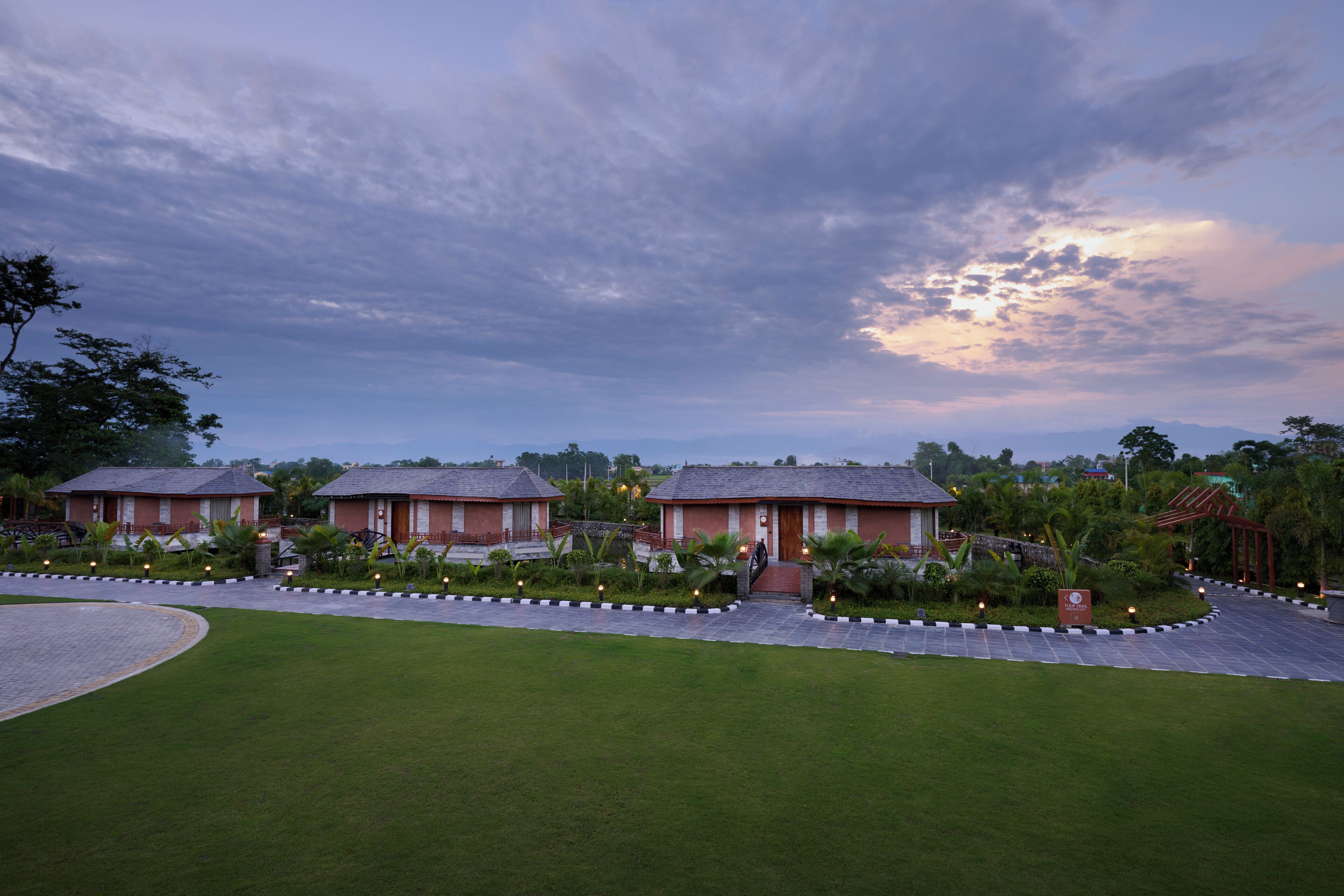 A resort with three bungalow-style buildings, a well-maintained lawn, and a paved walkway.