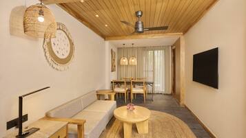 Una sala moderna con techo de madera, ventilador de techo, sofá, mesa de centro, televisor y un comedor con mesa y sillas.