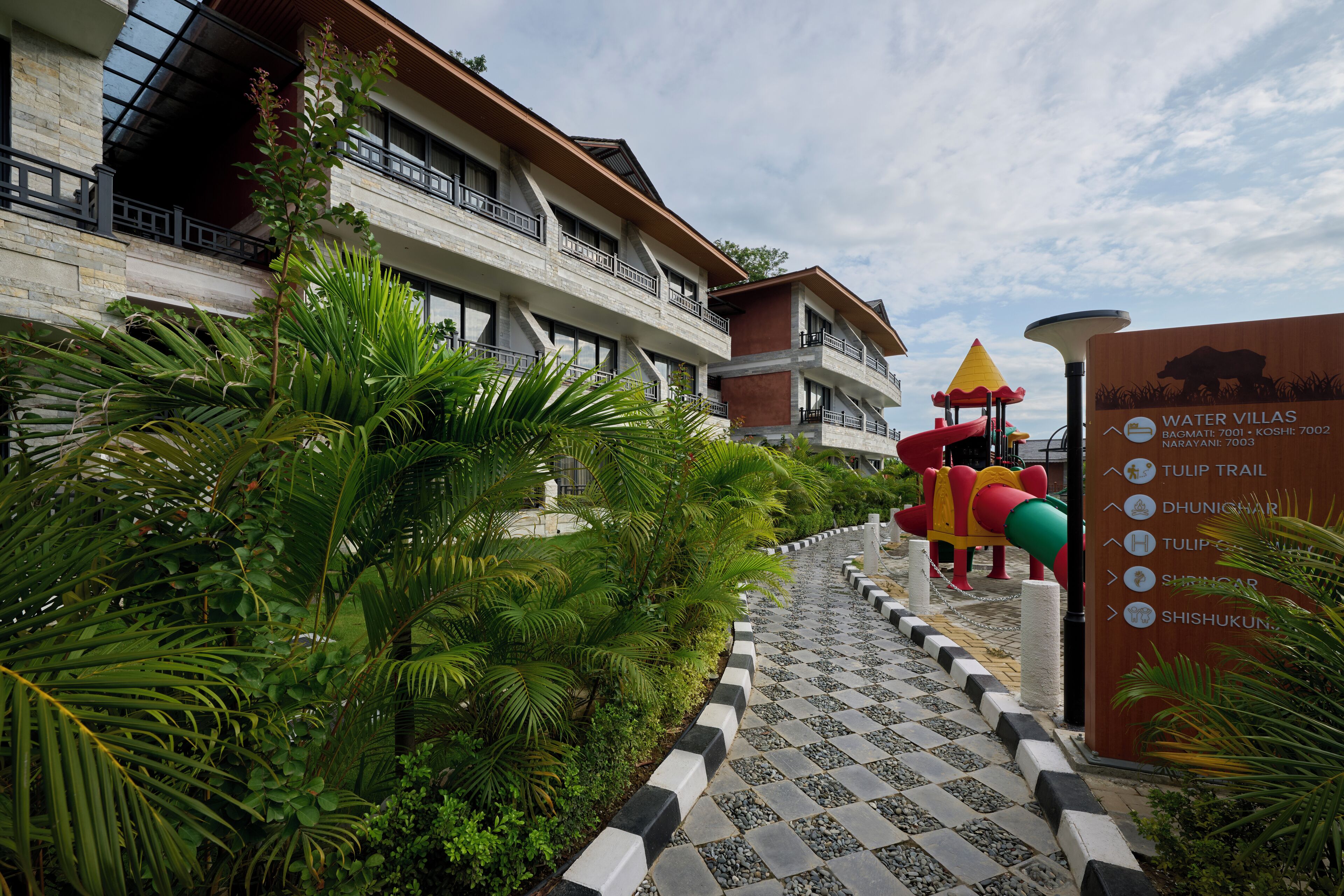 A hotel entrance with a sign listing amenities like a tulip trail and dhunichar.